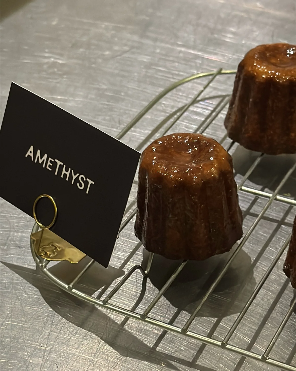 Canelé pastries on a cooling rack at Amethyst